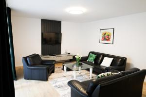 a living room with black leather furniture and a tv at Nest apartament in Peje