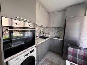 a kitchen with white cabinets and a washer and dryer at Sweet Escape Varna in Varna City