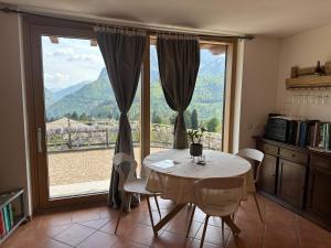 a dining room with a table and a large window at Pulsà dol Sìndec in Vilminore