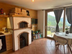 a kitchen with a fireplace and a table and a table and a dining room at Pulsà dol Sìndec in Vilminore