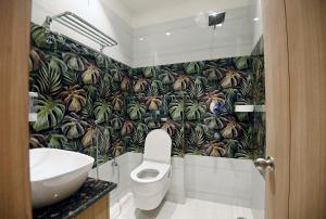a bathroom with a toilet and a tropical wallpaper at hotel arya inn in Prayagraj