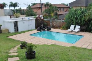 a small swimming pool in a yard with two lawn chairs at 34 on Milkwood in Durban +21 photos