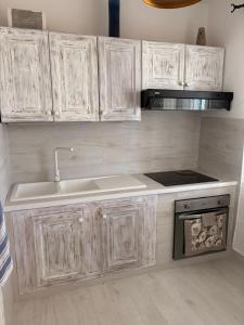 a kitchen with white cabinets and a sink and a stove at House Mia in Cala Liberotto +51 photos