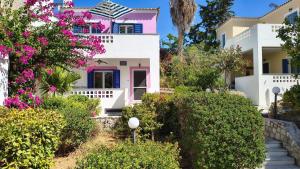 a pink and white house with flowers and bushes at Pink Villa in Porto Heli