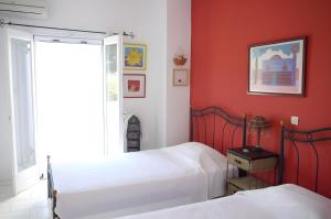 a bedroom with two beds and a red wall at Pink Villa in Porto Heli