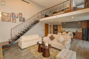 a living room with a couch and a staircase at Luxury Duplex & Apartment Pentstudio - Tay Ho Hanoi in Hanoi