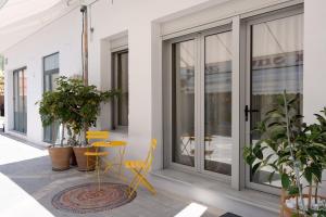 a patio with yellow chairs and a table and windows at Lixouri Square Loft in Lixouri