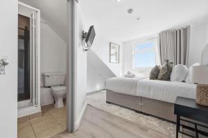 a white bedroom with a bed and a toilet at The Forest- Deepwood in Cambridge