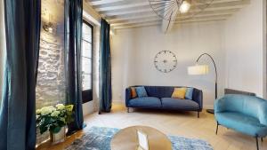 a living room with a blue couch and a clock at Le Petit Piron in Dijon