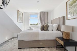 a white bedroom with a large bed and a window at The Forest- Deepwood in Cambridge