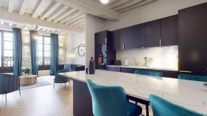 a kitchen with a large white counter and blue chairs at Le Petit Piron in Dijon