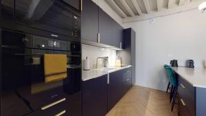 a kitchen with black cabinets and white counter tops at Le Petit Piron in Dijon