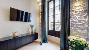 a living room with a television and a window at Le Petit Piron in Dijon