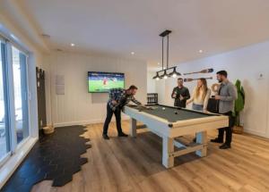 a group of people standing around a pool table at Spa & Sauna Pool Table & Game Room - Le Perche in Brownsburg