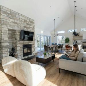 a woman sitting on a couch in a living room with a fireplace at Spa & Sauna Pool Table & Game Room - Le Perche in Brownsburg +30 photos