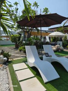 two blue chairs and an umbrella in a yard at The beach house, Baroro Beachfront Villa in Bacnotan