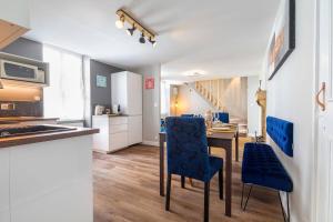 a kitchen and dining room with blue chairs and a table at Le Duplex des Ducs in Dijon