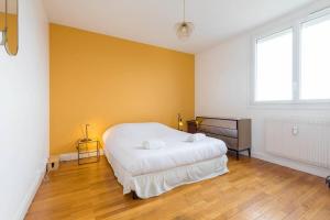 a bedroom with a white bed and a yellow wall at La Parenthèse in Dijon