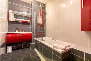 a bathroom with a white tub and a red sink at La Parenthèse in Dijon