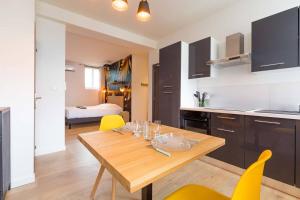 a kitchen and dining room with a wooden table and yellow chairs at L'essentiel in Le Creusot