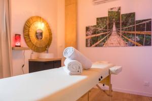 a room with a bed and a mirror and towels at L'essentiel in Le Creusot
