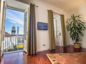 a room with a large window with a view of a clock tower at Comercial Boutique Guest House in Ponta Delgada