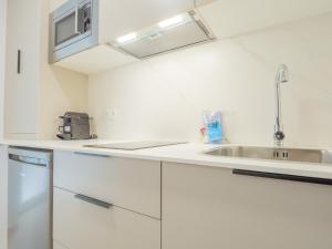 a white kitchen with a sink and a microwave at YBH Villa Lara in Villanueva de Arosa