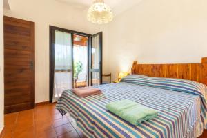 a bedroom with a bed with a striped blanket and a chandelier at Villa Terry in Marongiu
