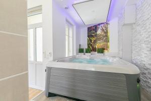a bathroom with a tub with a painting on the wall at Le Relax SPA in Dijon