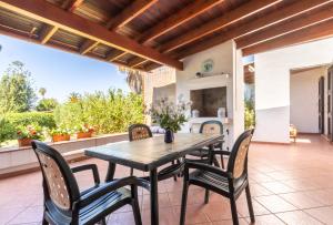 an outdoor dining room with a wooden table and chairs at Villa Terry in Marongiu