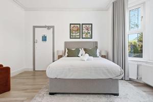 a white bedroom with a large bed with white sheets at The Forest- Blackwood in Cambridge