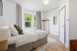 a white bedroom with a large bed and a window at The Forest- Blackwood in Cambridge