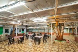 a room with tables and chairs and a tree at La PAVI RESORT in Auroville