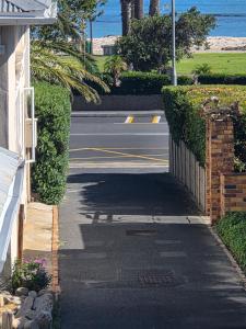 a street next to a house with a fence at Charla on the Beach in Gordonʼs Bay