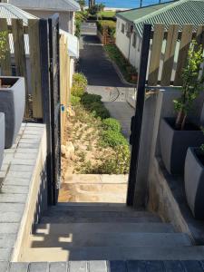 an open door to a street with a fence at Charla on the Beach in Gordonʼs Bay
