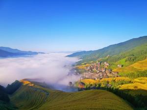 a foggy valley with a small town in the middle at Longji Forest Lodge--Terraced landscape from the room, Pick-up and drop-off service from Ping'an Village Parking Lot, Sunrise& Sunset in Heping