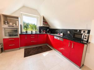 a kitchen with red cabinets and a window at Atik V Borovičkách in Lipuvka +3 photos