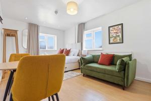 a living room with a green couch and a bed at The Forest-Wildwood in Cambridge
