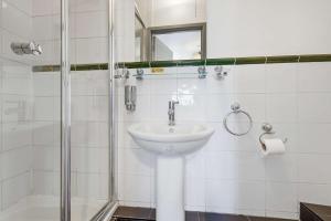 a white bathroom with a sink and a shower at The Forest-Wildwood in Cambridge