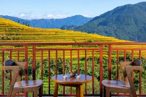 a table and chairs on a balcony with a view of mountains at Longji Forest Lodge--Terraced landscape from the room, Pick-up and drop-off service from Ping'an Village Parking Lot, Sunrise& Sunset in Heping