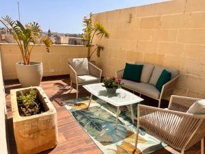 a patio with a couch and a table and chairs at Palazzo De La Sengle Boutique Hotel in Senglea