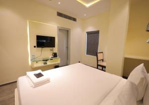 a bedroom with a white bed and a television at YAR INN CENTRAL in Vijayawāda