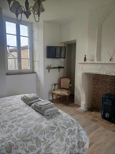 a white bedroom with a bed and a fireplace at Chambre d'hôtes - Retour à la ferme in Verteillac