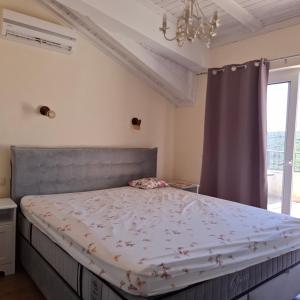 a bedroom with a bed with a gray headboard and a window at SUNTIME apartament 5 in Kotor