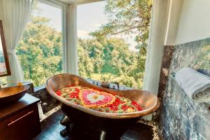 a bath tub filled with flowers in front of a window at Villa Kalisha - Romantic, Seclusion in the heart of Nature in Tegalalang