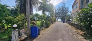 a dirt road with blue trash cans on the side of a house at The Rich Instantly Home in Sathani Huai Yang