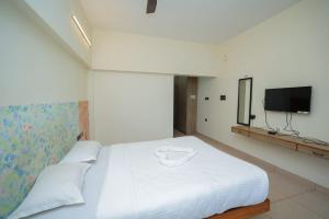 a bedroom with a white bed and a tv at La PAVI RESORT in Auroville