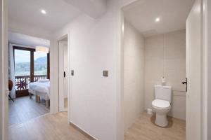 a white bathroom with a toilet and a bedroom at L'Echo des Montagnes Armoy in Armoy