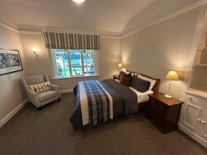 a bedroom with a bed and a chair and a window at Amberley Lodge in Amberley