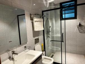 a bathroom with a shower and a sink and a toilet at Masaki Cozy Stay in Dar es Salaam